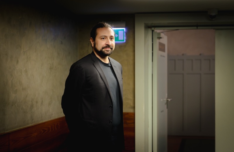 Francesco Bossaglia backstage in a corridor, relaxed half-smile.