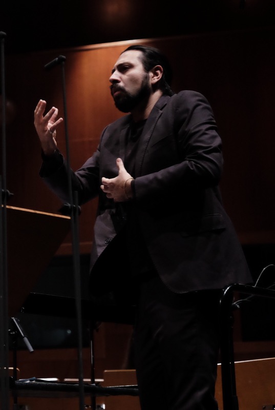 Francesco Bossaglia in close-up, warm light, hand raised, thoughtful expression.